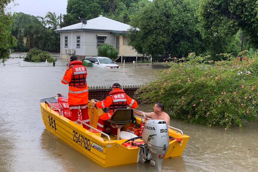 A man sits in a SES rescue boat with two rescuers.