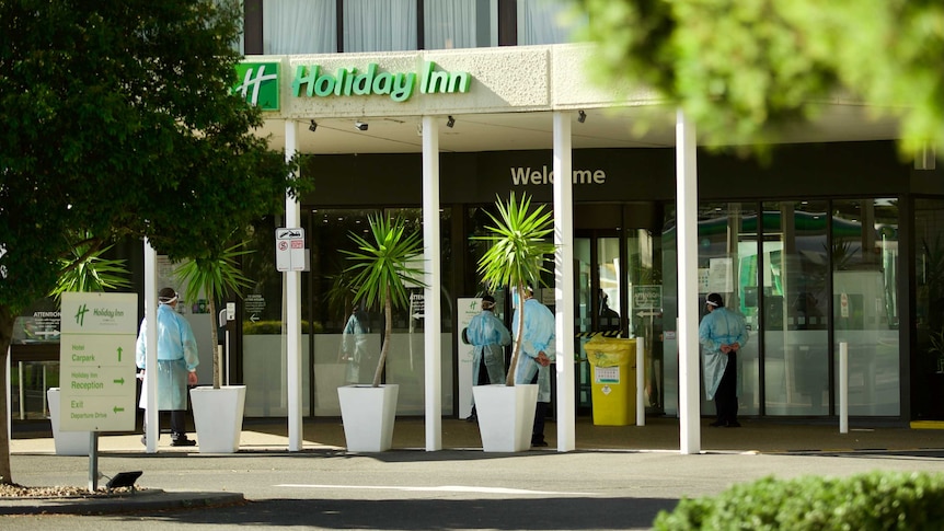 People in full PPE stand outside a Holiday Inn hotel.