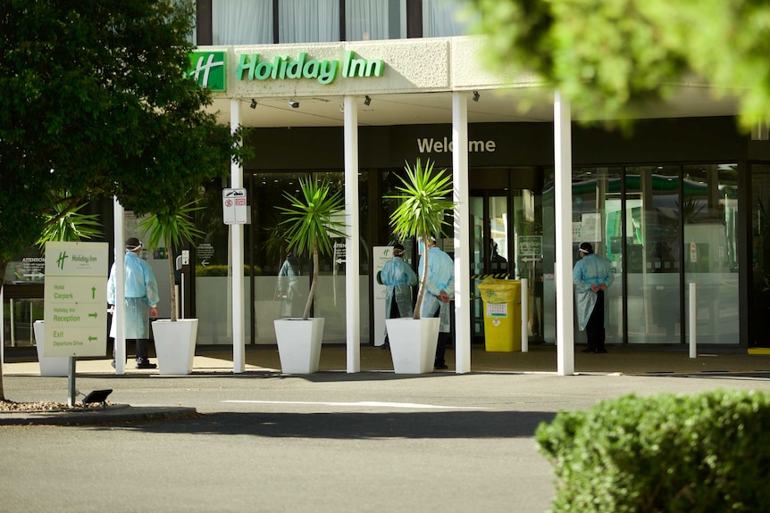 People in full PPE stand outside a Holiday Inn hotel/