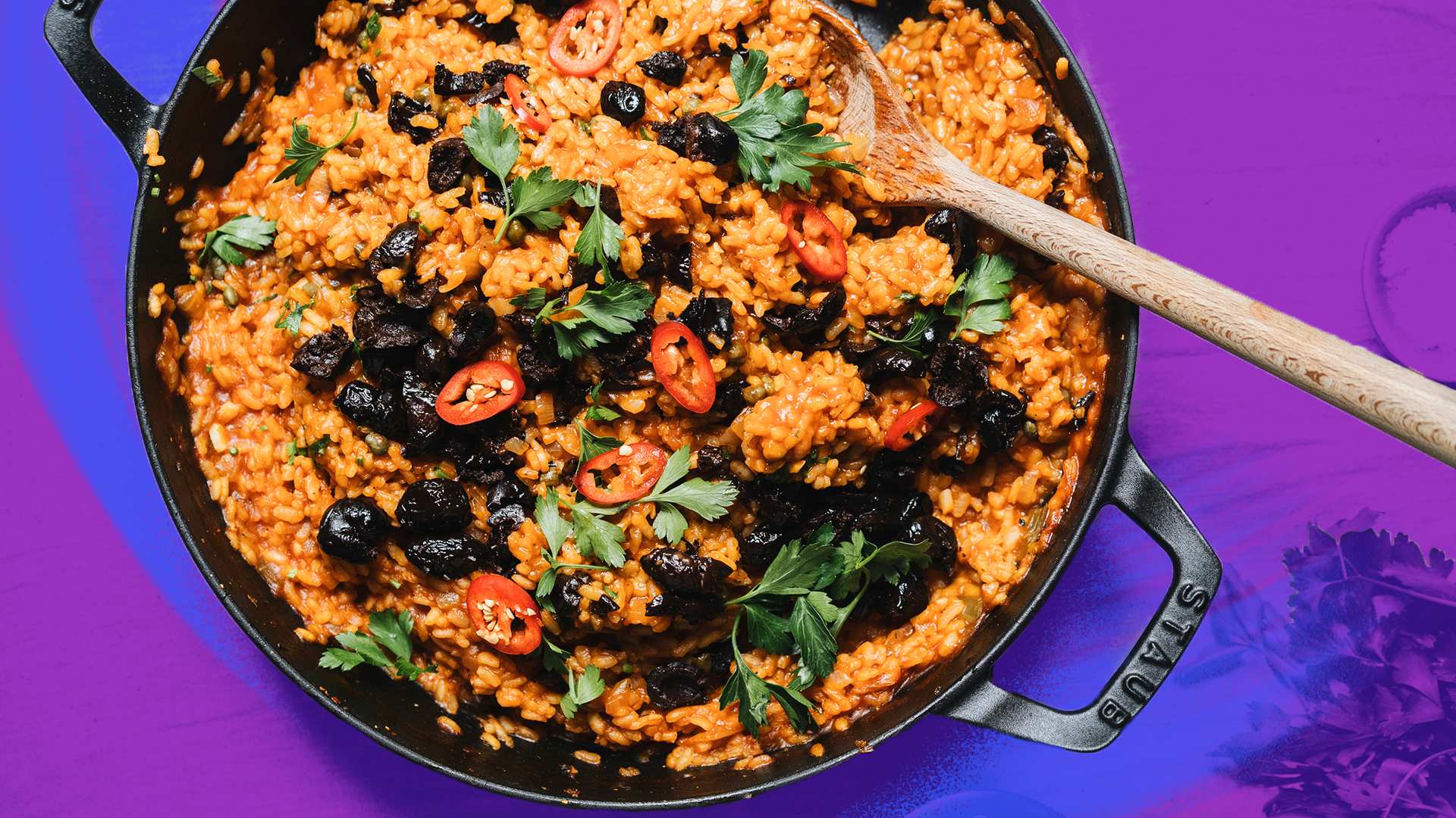A pot of baked puttanesca risotto topped with chopped chilli, olives and parsley, a one-pot dinner recipe.
