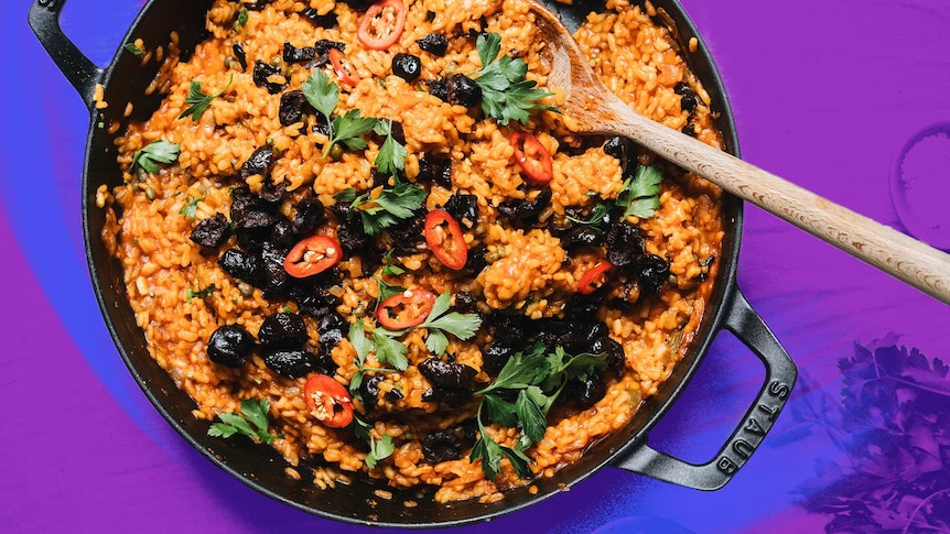 A pot of baked puttanesca risotto topped with chopped chilli, olives and parsley, a one-pot dinner recipe.