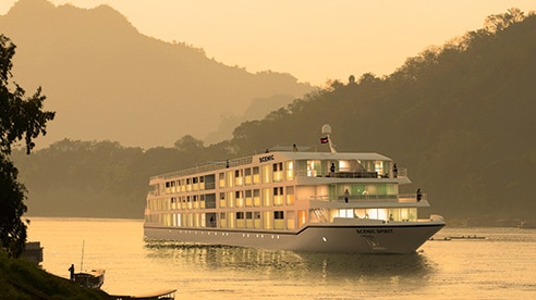 A boat floats down a misty river.