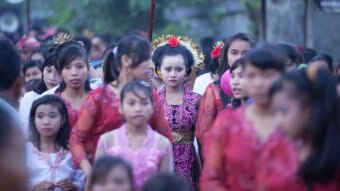 A group of Indonesian girls and young women stand in traditional attire.