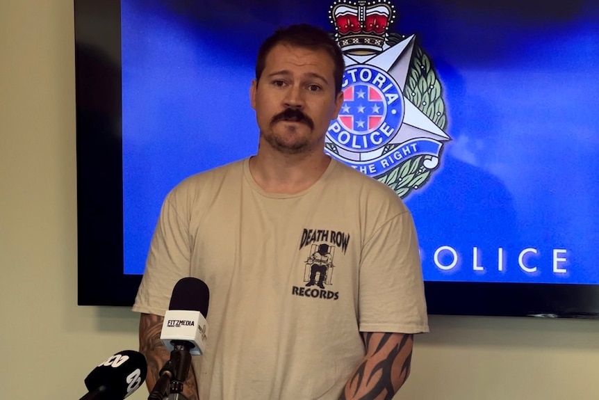 Man stands in front of police sign