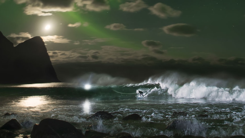 Mick Fanning surfs a wave beneath the Northern Lights in Norway. Supplied: Red Bull Content Pool