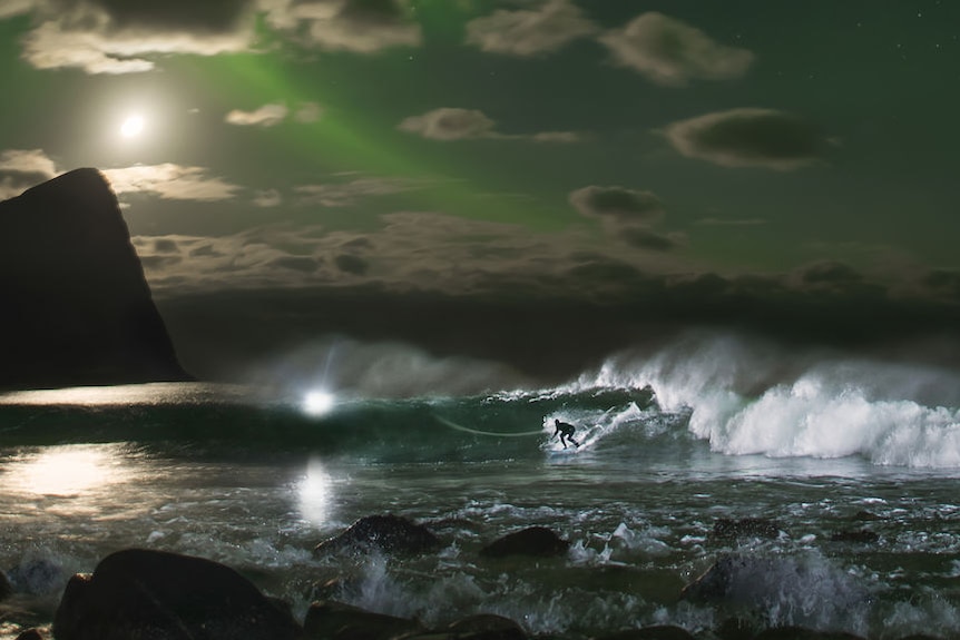 Mick Fanning surfs a wave beneath the Northern Lights in Norway