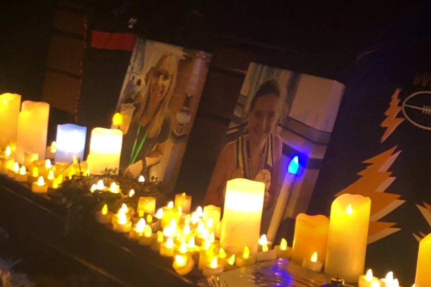 Portraits of Julie and Jessica Richards are propped up in the dark, with candles surrounding both pictures.