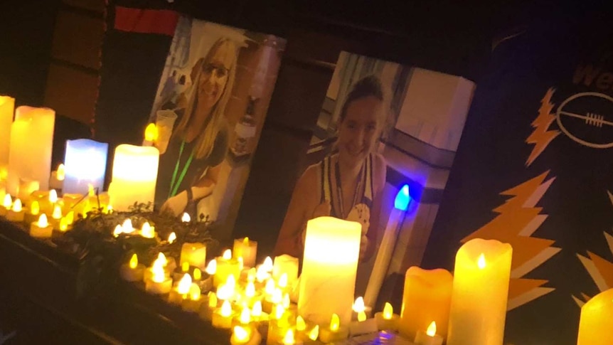 Portraits of Julie and Jessica Richards are propped up in the dark, with candles surrounding both pictures.