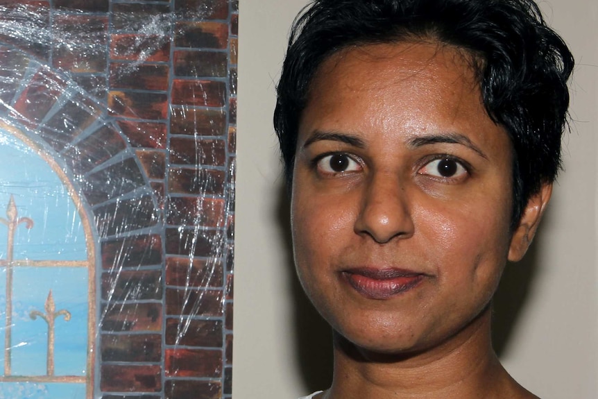 A tight head shot of Chamari Liyanage standing next to a painting.