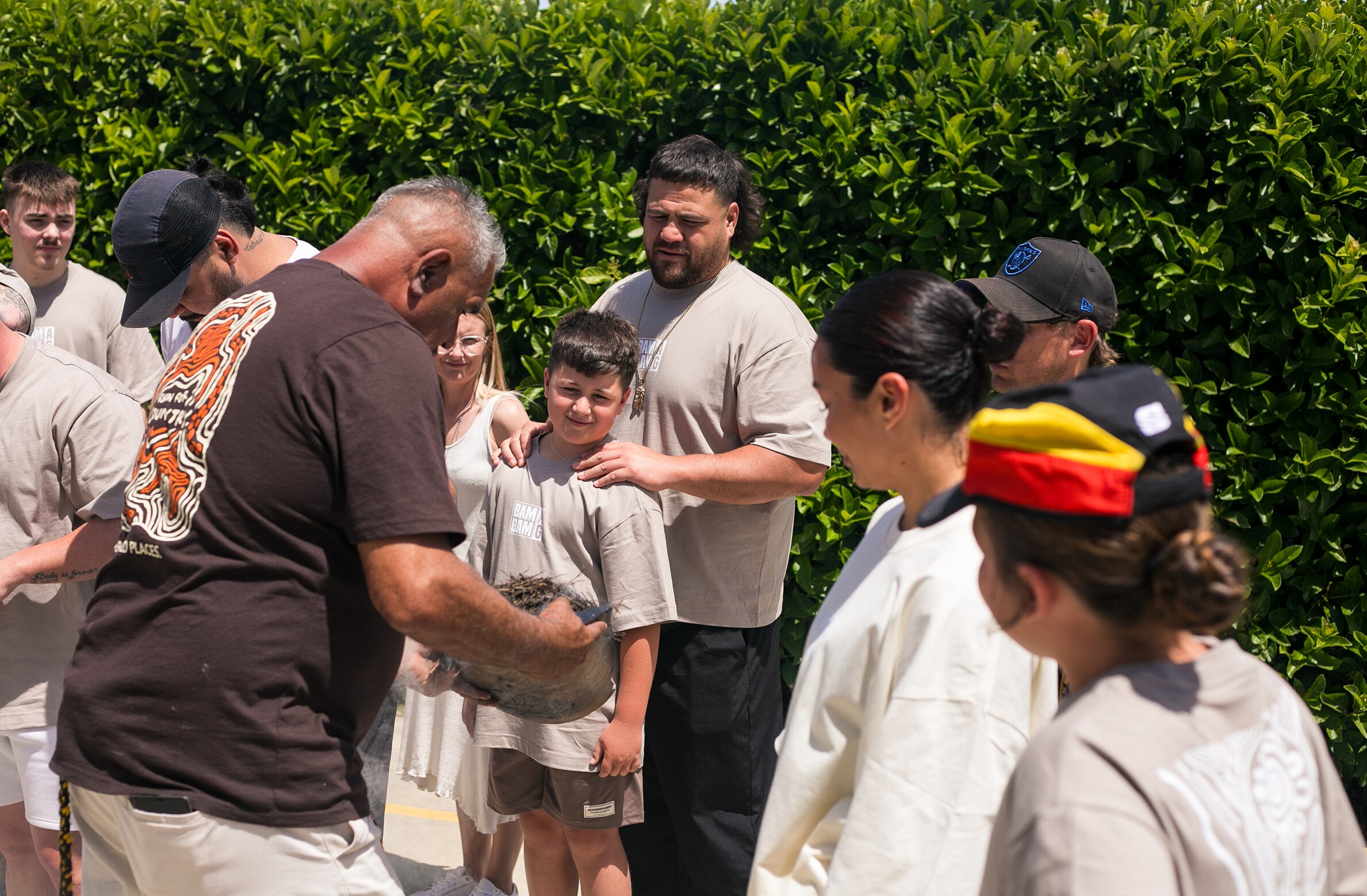 An aboriginal elder holds the leaves and ingredients for a traditional smoking ceremony while others in attendance watch