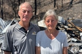 Greg and Petria stack look into the camera with some of their destroyed house behind them.