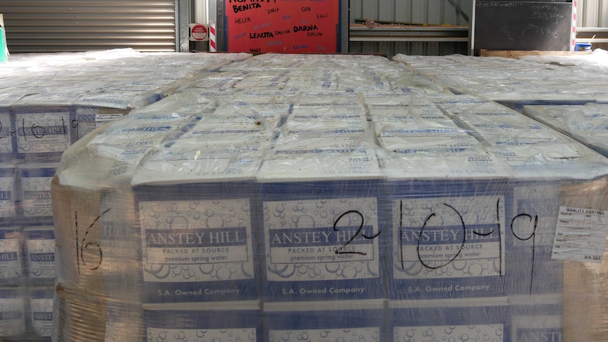 Plastic-wrapped pallets of boxed water sitting in a warehouse.