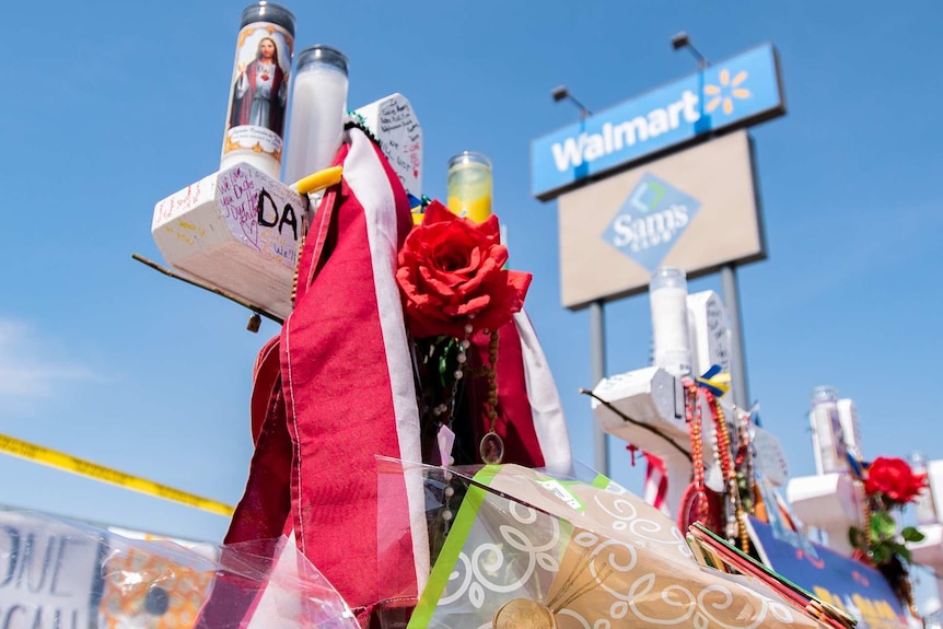 A cross covered with flowers and love notes sits in the parking lot of the Walmart in El Paso, Texas.