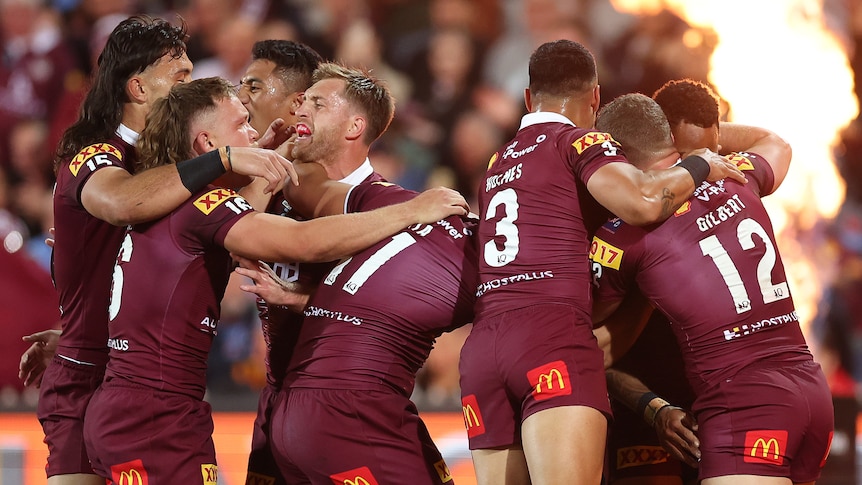 Queensland male State of Origin players embrace as they celebrate a try against NSW.