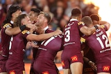 Queensland male State of Origin players embrace as they celebrate a try against NSW.