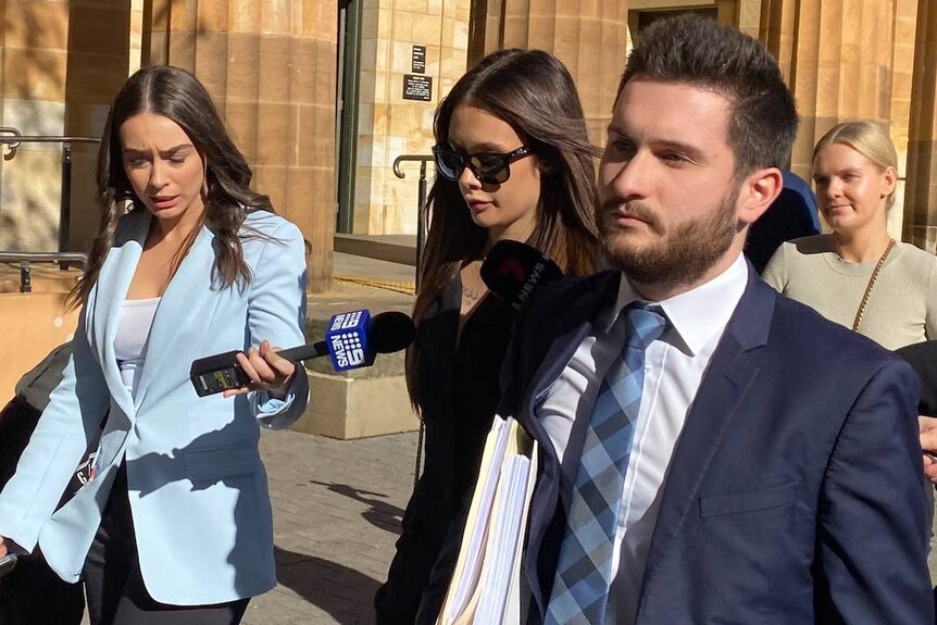  A young woman flanked by media outside an Adelaide court.