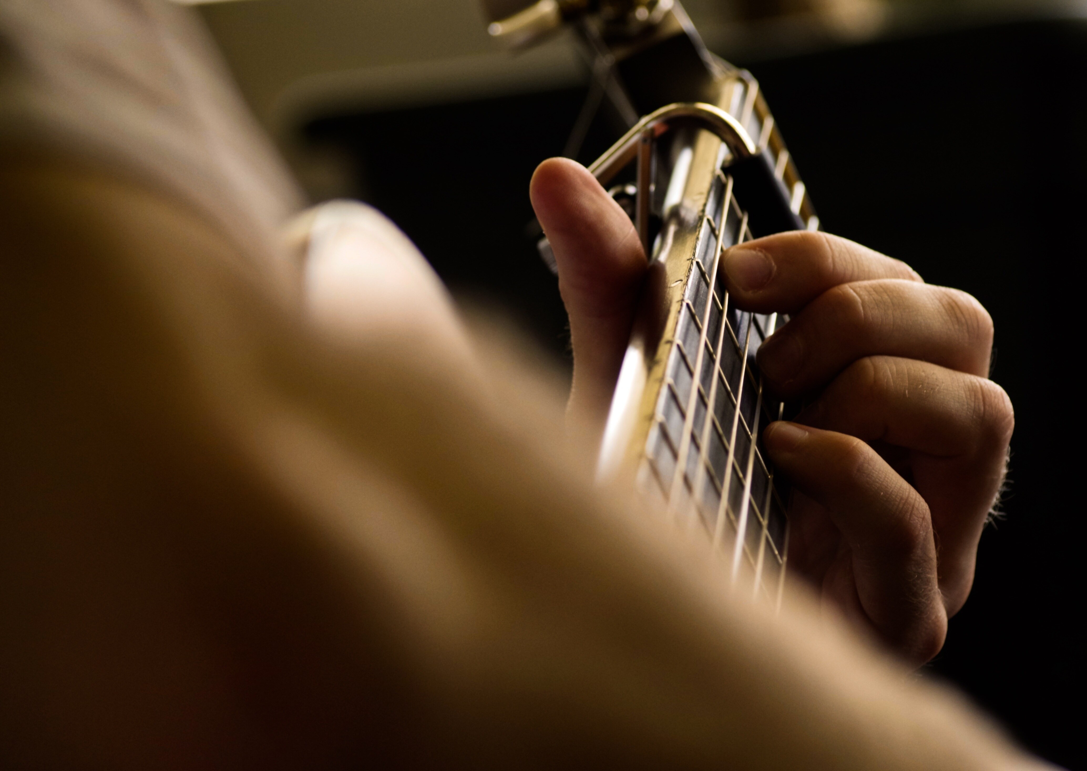 Close up of someone playing guitar in dimly lit space