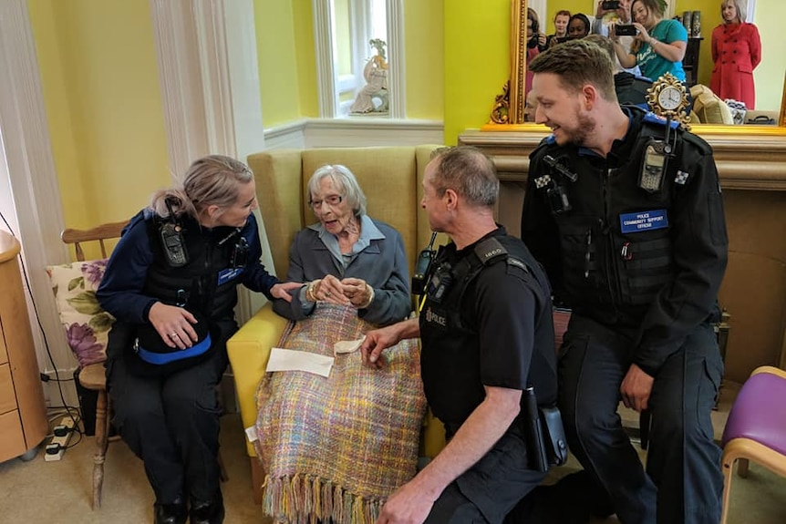 Anne Brokenbrow sits in a chair as a police officer puts handcuffs on her.