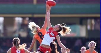 Female players reach for the football during an AFL game.