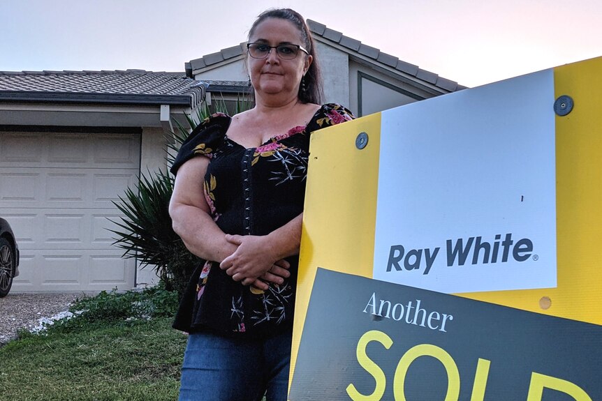 Kerri Rye standing by the sold sign outside her rental property