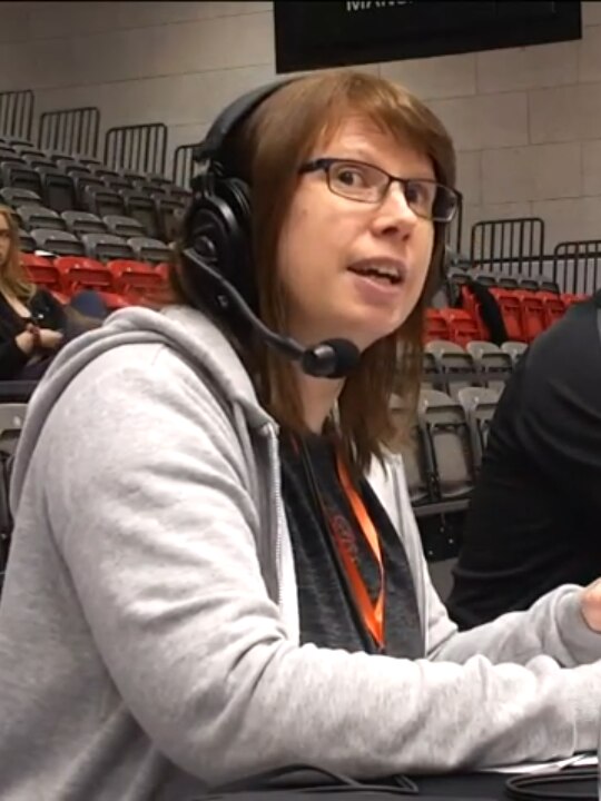 A woman wearing headphones with a microphone commentates