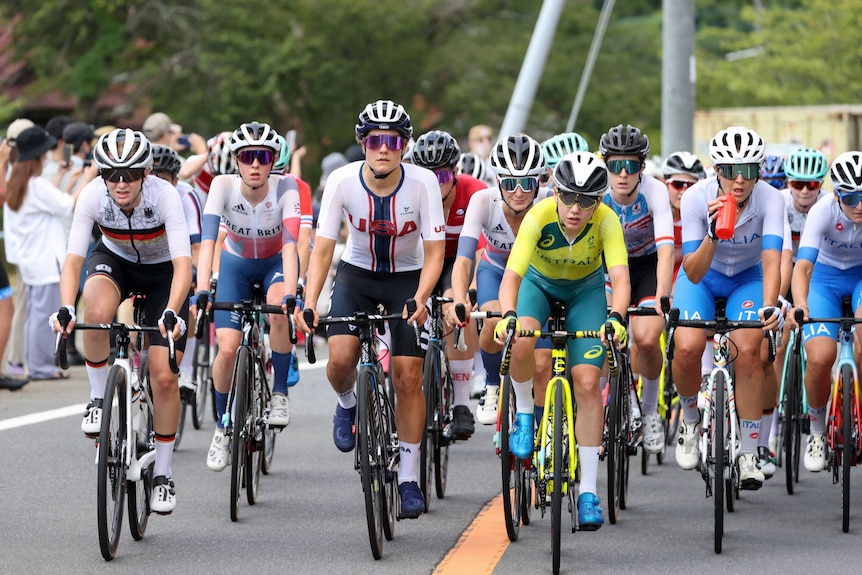 A front on shot of a pack of women on bicycles in the Women's Road Race at the Olympics.