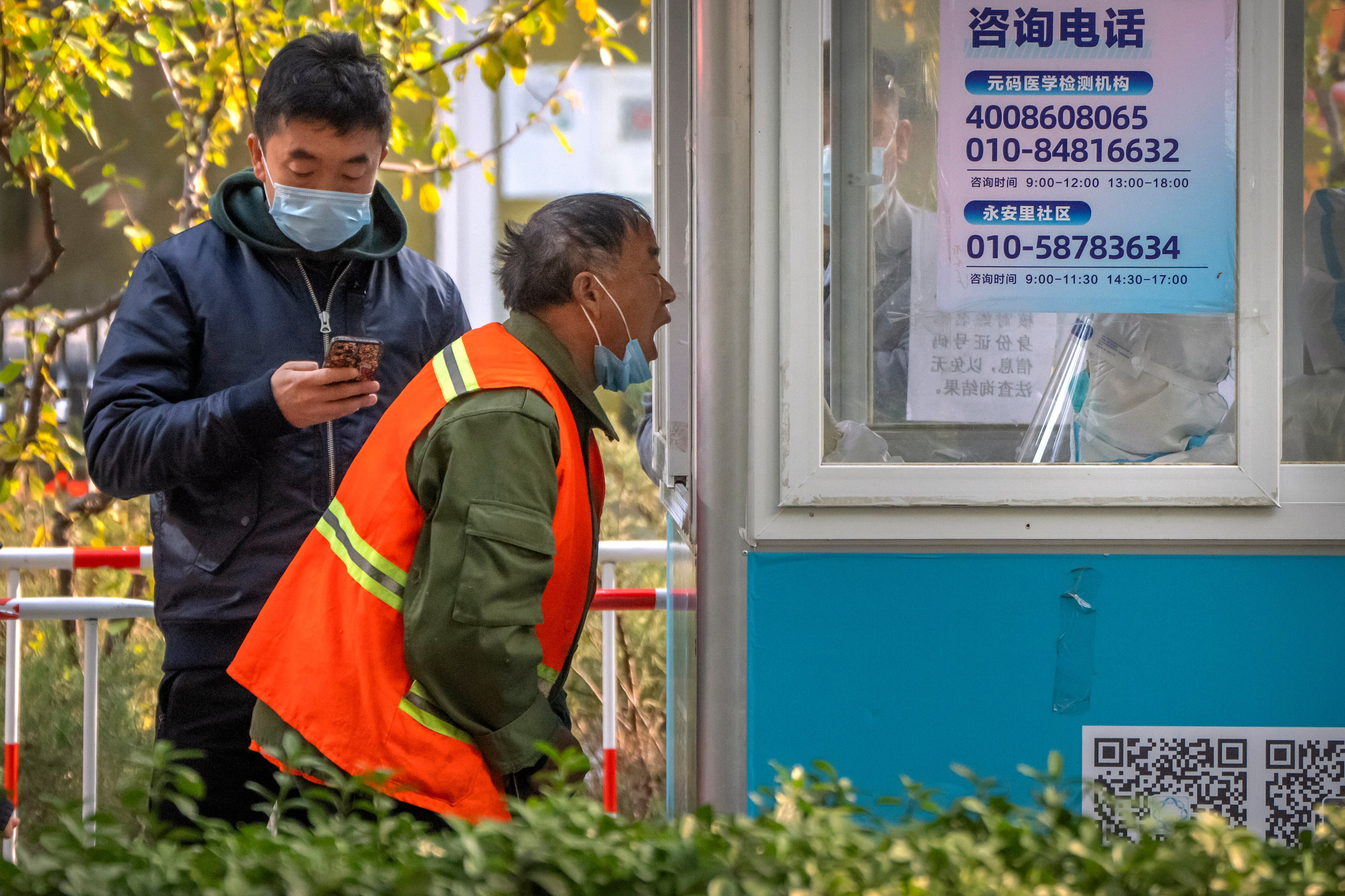 一名环卫工人正在一处核酸检测亭做核酸检测