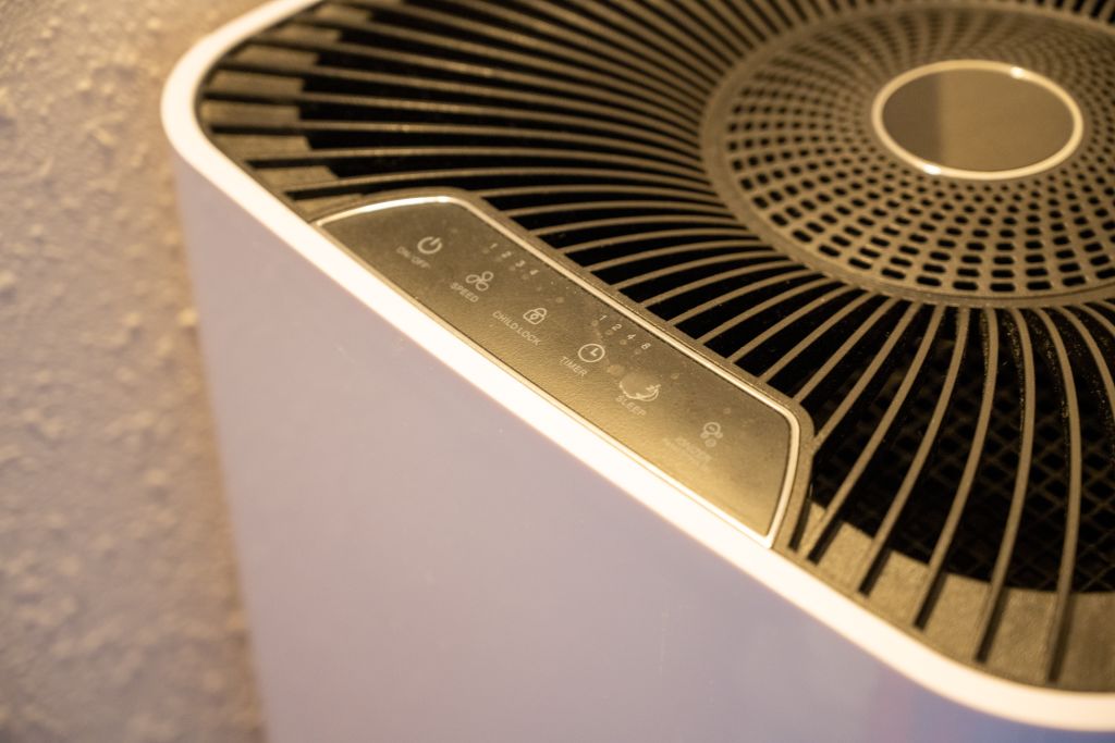 Close-up of part of a grey and white air purifier.