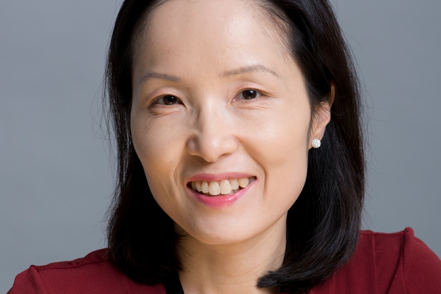 A woman smiles for the camera against a blank background