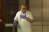 A man screams and holds his hand to his chest as he walks out hotel doors