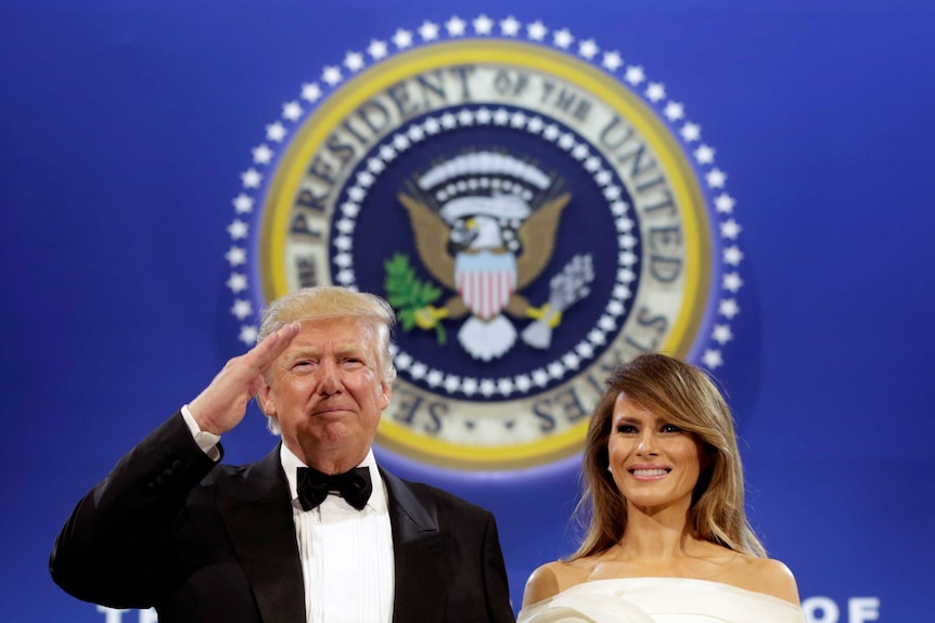 US President Donald Trump salutes with his wife Melania