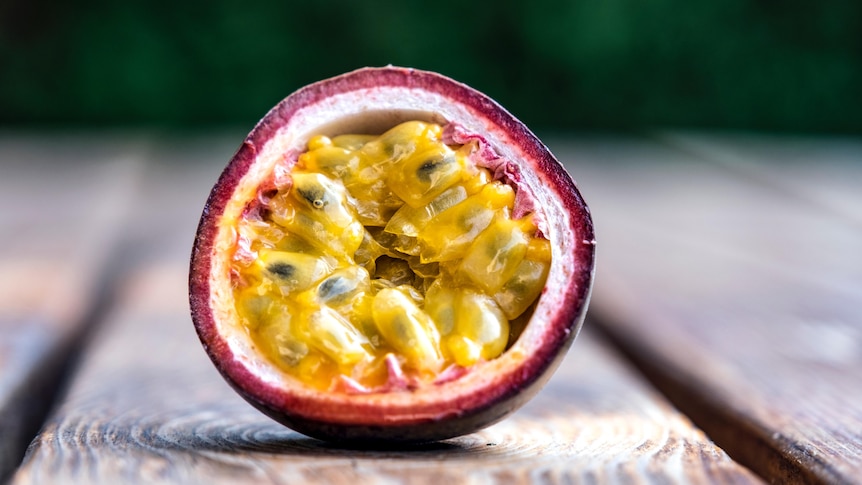 A single passionfruit, cut in half, is sat on a table.