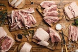 different cuts of pork are arranged on wooden chopping boards