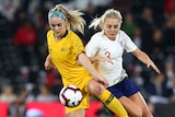 Matildas player Ellie Carpenter competes with Lionesses player Alex Greenwood for the ball during a football match.