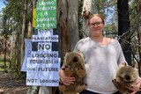 South Brooman Forest resident Takesa Frank, holding two toy wombats, at the Brooman Campout with anti-logging signs