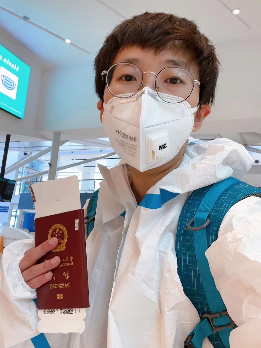 A young lady wearing glasses and mask holding a Chinese passport