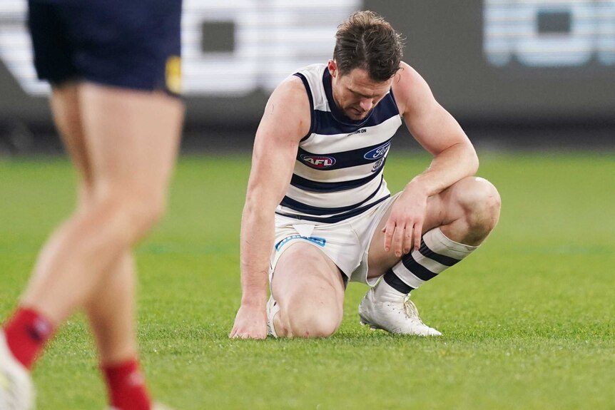 Patrick Dangerfield is on his haunches, looking down towards the turf