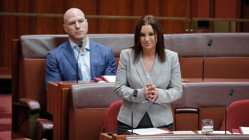 David Pocock sits behind Jacqui Lambie while she speaks in the senate