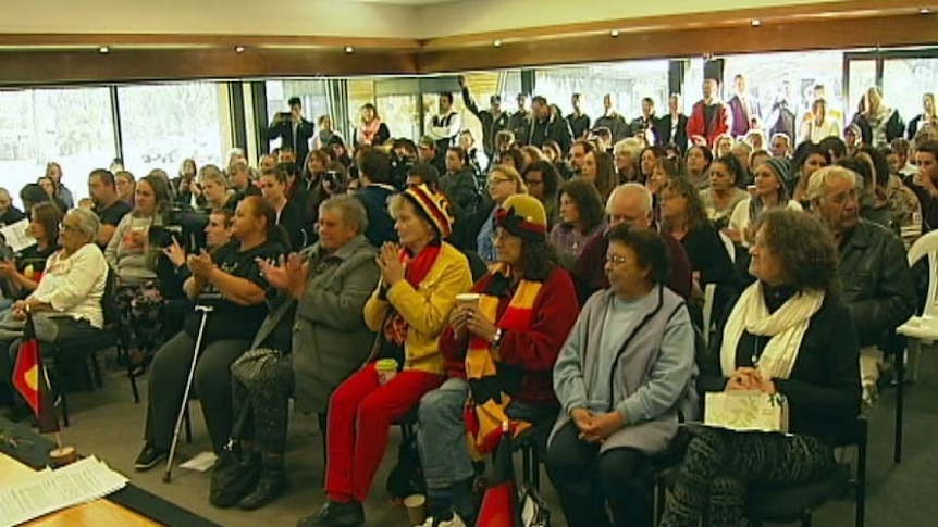 Many members of the Tasmanian Indigenous community clap during a meeting.