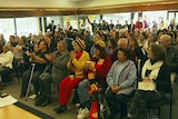 Many members of the Tasmanian Indigenous community clap during a meeting.