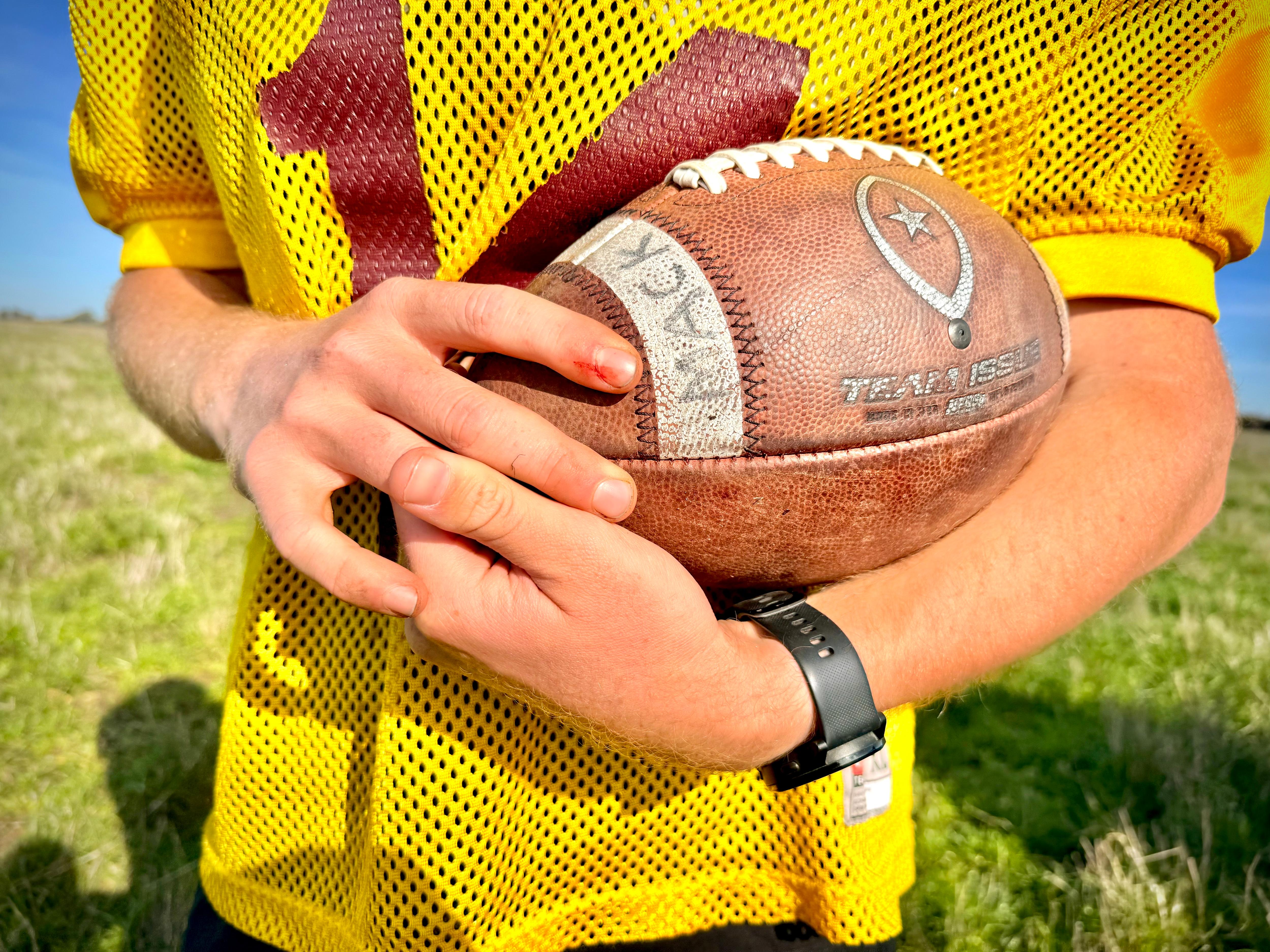 A red headed 19-year-old boy with a football on a farm.