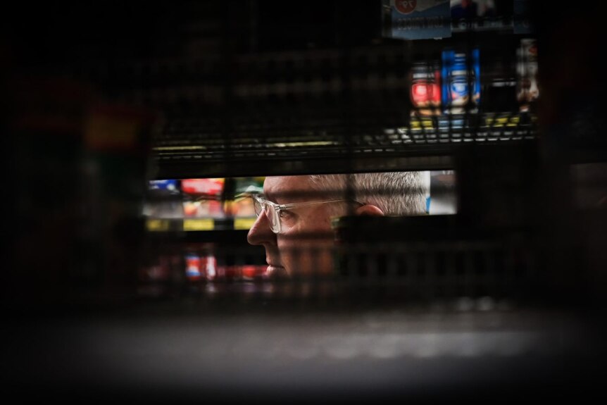 Paul Smith's face between dark grocery shelves