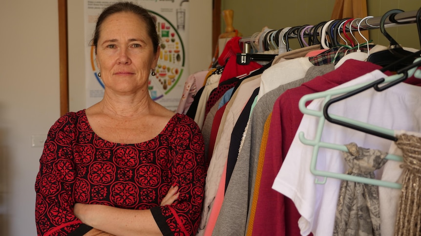 Woman stands next to rack of clothes