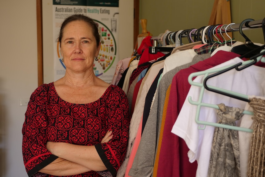 Woman stands next to rack of clothes