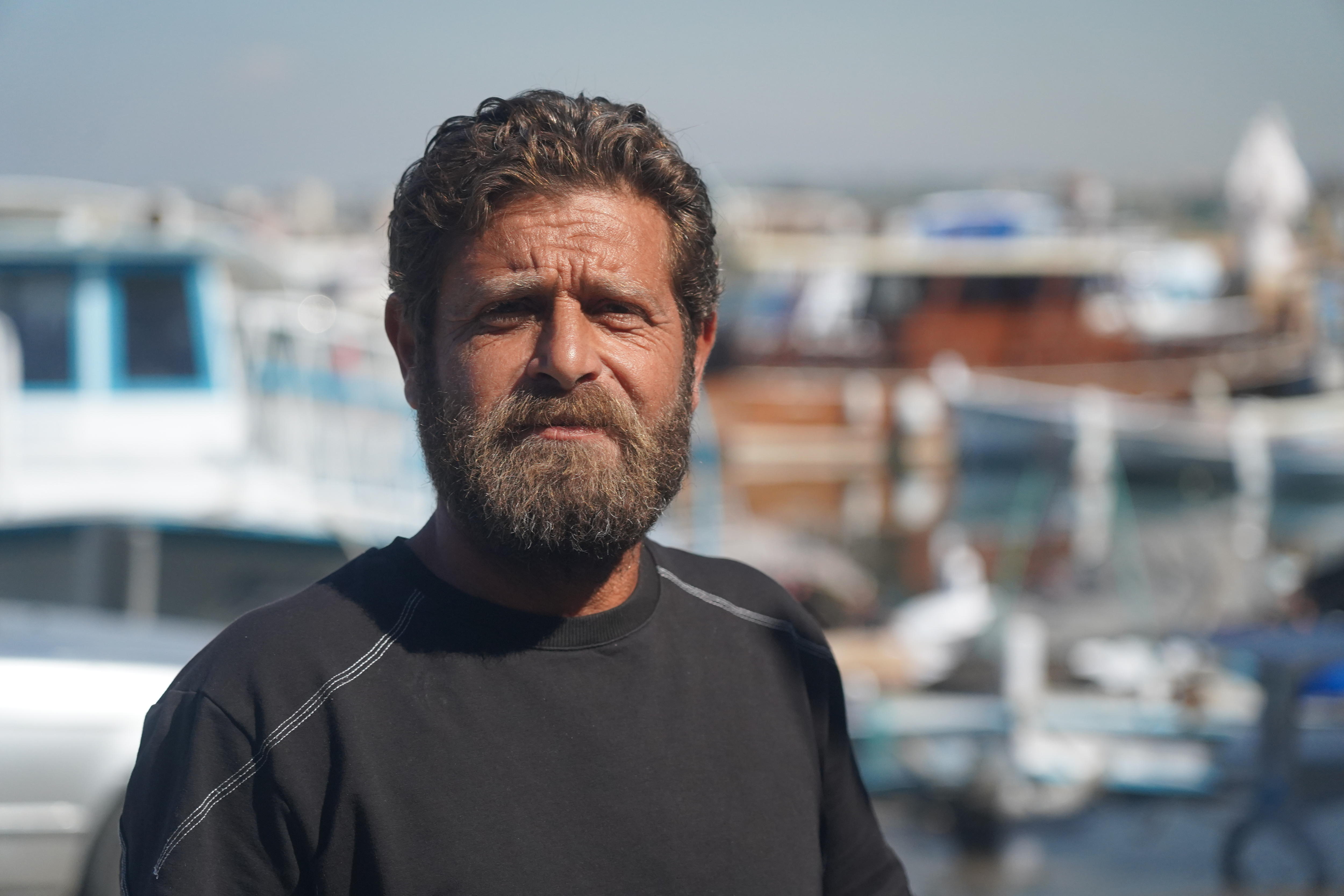 A man poses for a photo with a full wharf behind him