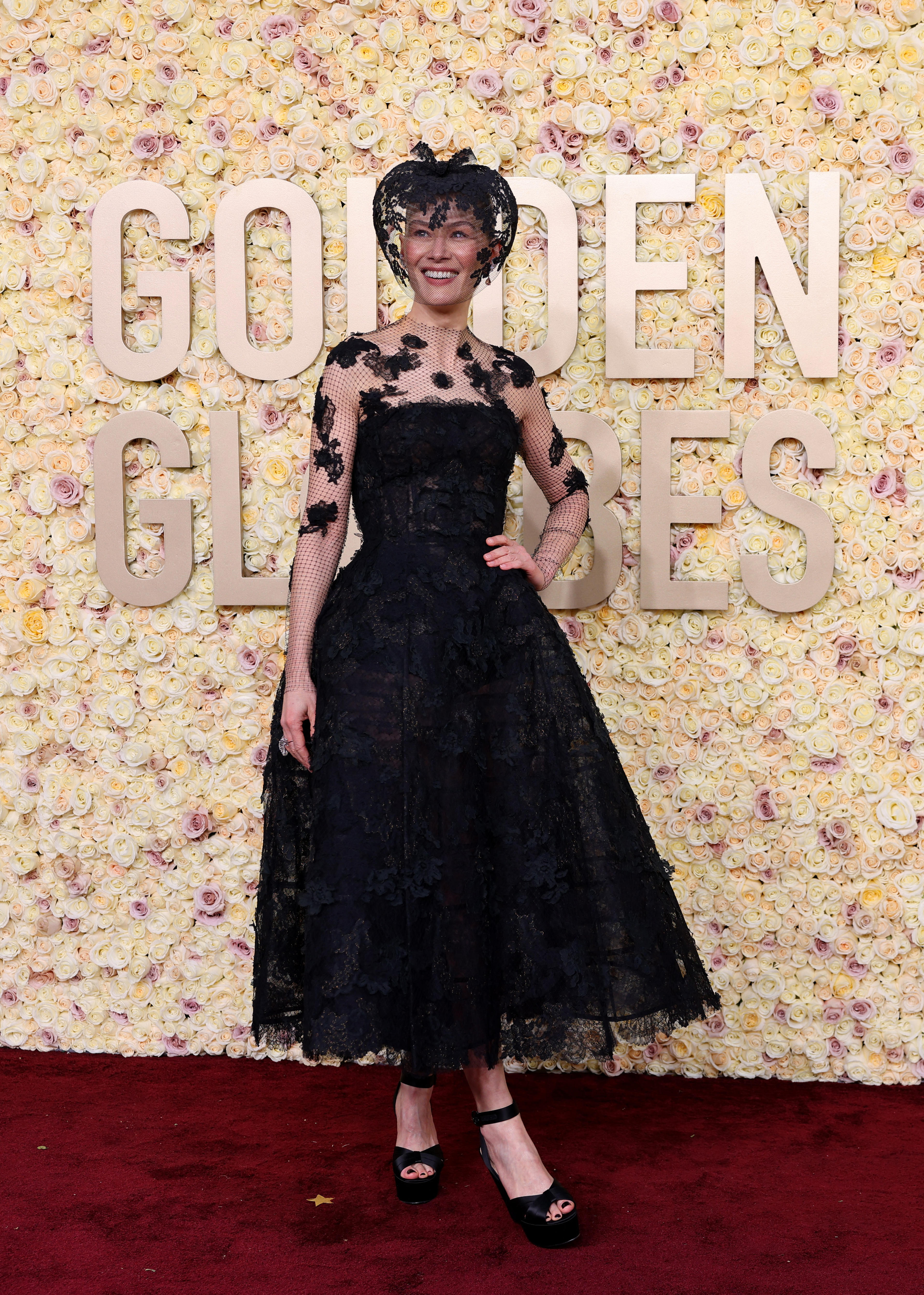 An actress on the red carpet in a black gothic dress with a headpiece