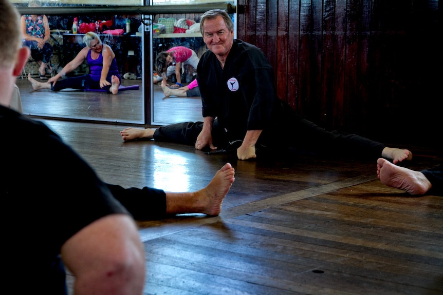 Taekwondo teacher Ian Fauth looks at the camera while doing the splits.