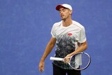 John Millman closes his eyes, looks disappointed, as he holds his racket loosely, standing on the blue court