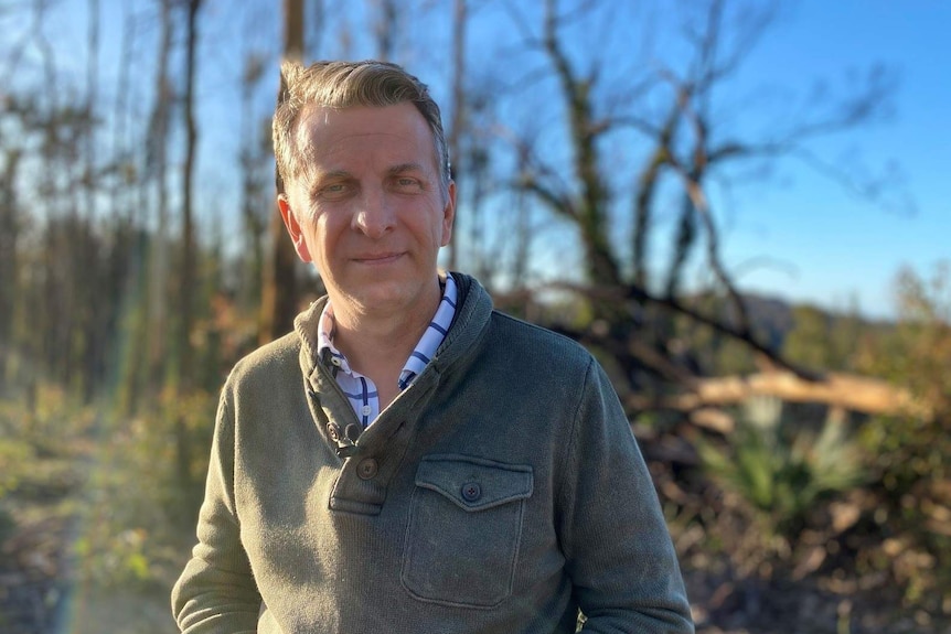 Andrew Constance with blackened trees in the background.