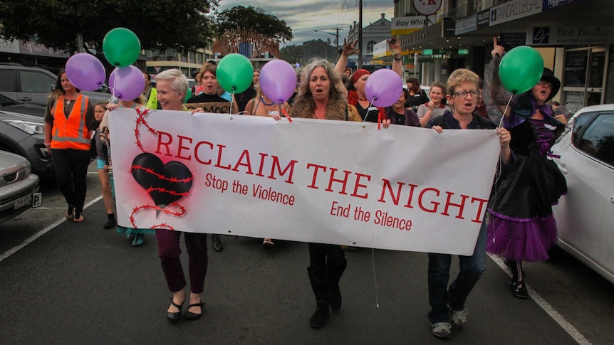 Women carrying the Reclaim the Night banner while marching through Lismore